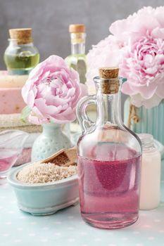 Flakon z różową wodą na tle piwonii