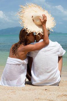 Para całująca się pod kapeluszem na plaży