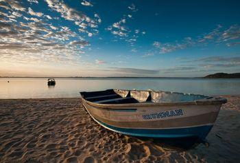 Porzucona łódź na piaszczystej plaży nad jeziorem 