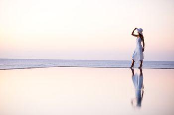 Kobieta w białej sukience spacerująca na krawędzi basenu