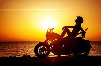 Kobieta siedząca na motocyklu na tle zachodzącego słońca