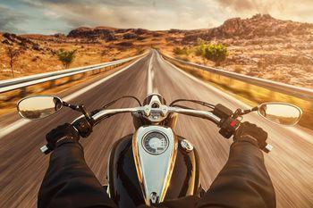 Motocyklista jadący pustą drogą