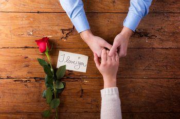 Splątane dłonie pary, róża i list