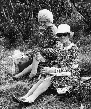 Dwie starsze panie siedzące na trawie