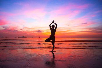 Kobieta uprawiająca jogę przy zachodzie słońca