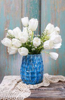 Białe tulipany w niebieskiej wazie