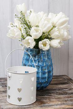 Białe tulipany w niebieskim flakonie