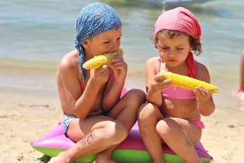 Dzieci jedzące kukurydze na plaży