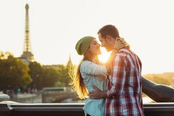 Para przytulająca się na tle Wieży Eiffla