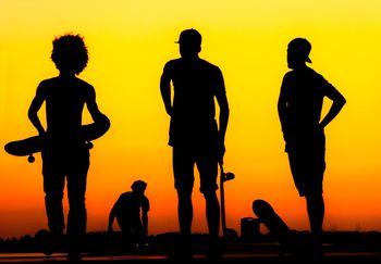 Młodzież jeżdżąca na deskorolce o zachodzie słońca