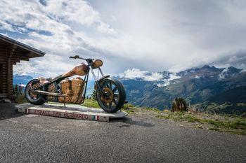 Drewniana rzeźba przedstawiająca motocykl na tle Alp