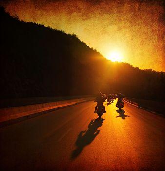 Grupa motocyklistów jadących ulicą o zachodzie słońca