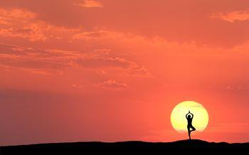 Kobieta ćwicząca jogę o zachodzie słońca